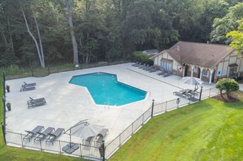 an aerial view of a stamped concrete pool with lounge chairs and umbrellas
